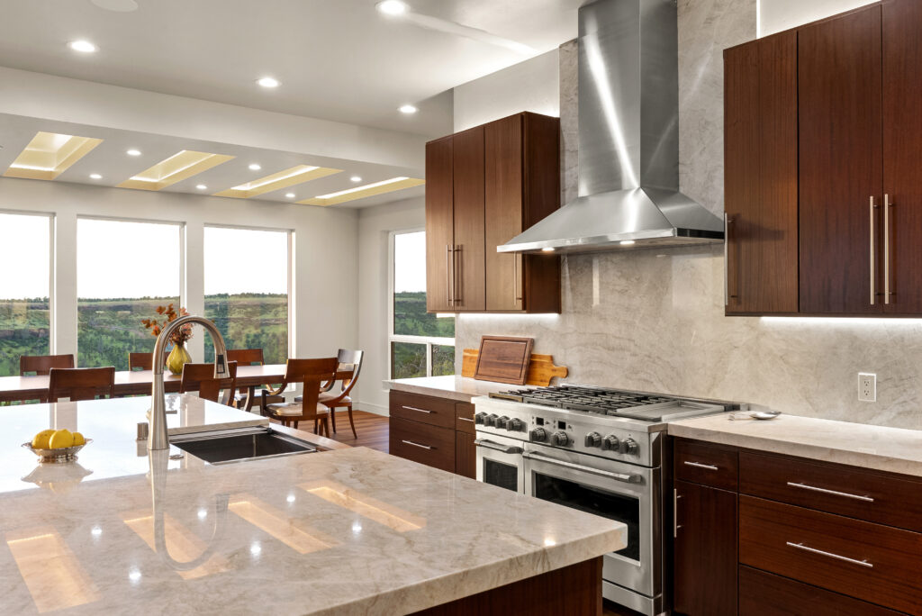 Close-up of modern kitchen with marble island and stainless steel appliances.
